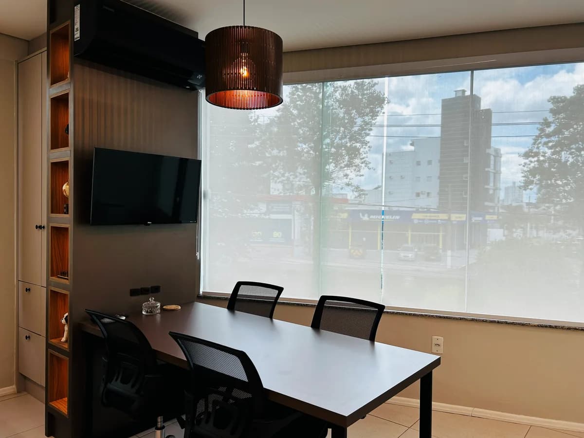Sala de reunião da Geziane Maciel, com mesa, cadeiras e janela para a cidade de Lages